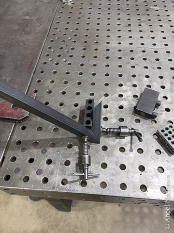 Two pieces of tube cut at the correct angle and clamped to a block on a fixture table